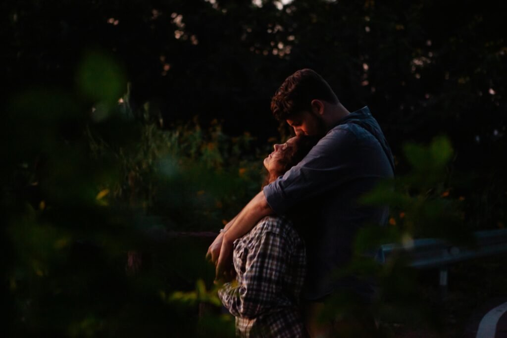 A couple shares a tender embrace in a peaceful forest at sunset, surrounded by nature.